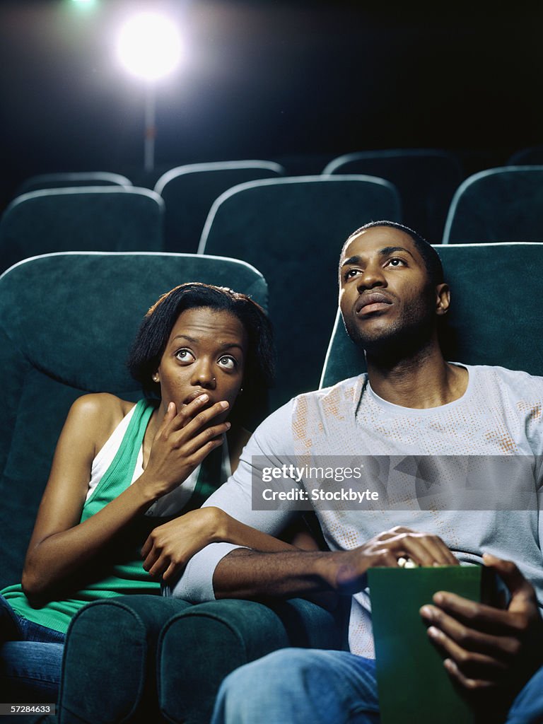Young couple sitting in the theatre and watching a movie
