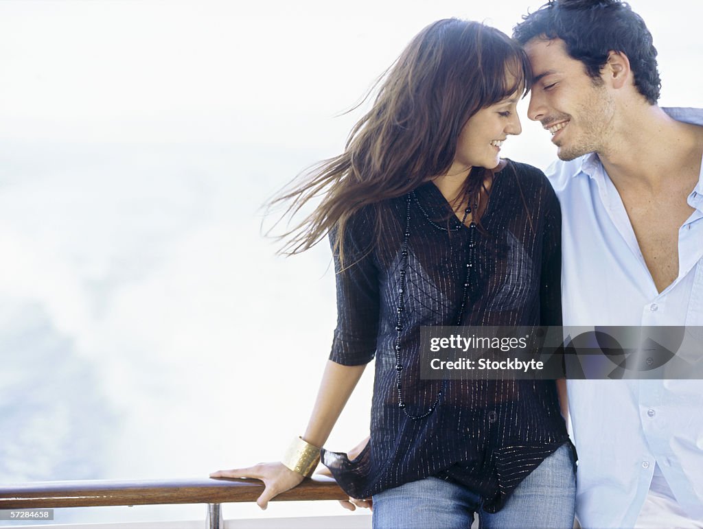 Young couple standing leaning against a railing of a boat