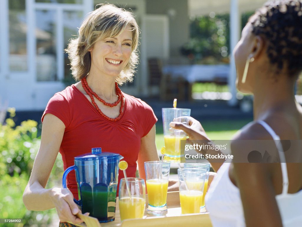 Young woman offering juice to a mid adult woman