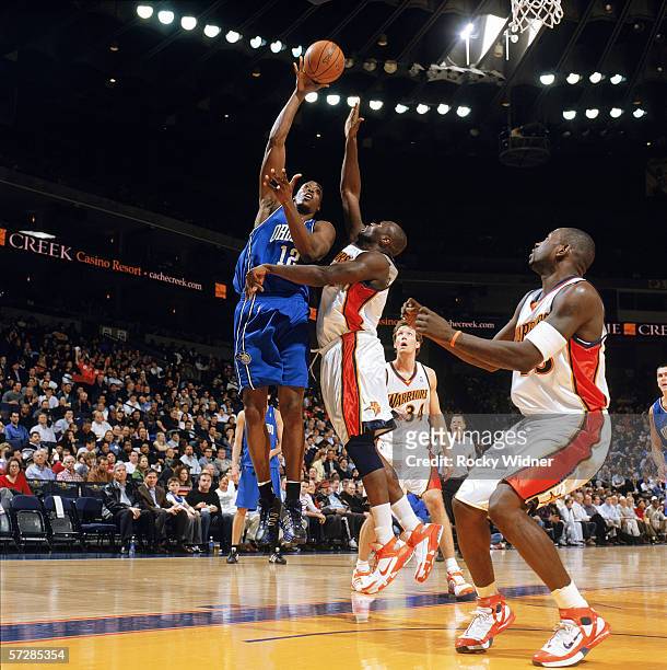 Dwight Howard of the Orlando Magic shoots over Adonal Foyle of the Golden State Warriors at The Arena in Oakland on March 1, 2006 in Oakland,...