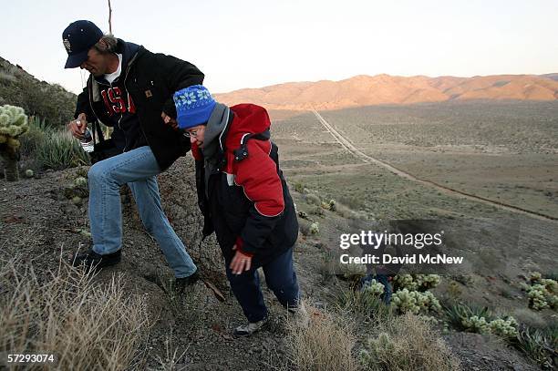 Minutemen Steve Callagy and Bea Mitchell climb a steep hill to their nighttime post overlooking the border fence dividing the U.S. From Mexico as...