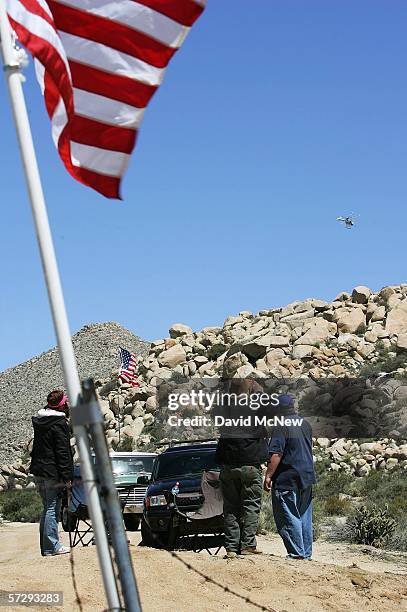 Minutemen watch a border patrol helicopter hovering near the border as Minuteman Civil Defense Corps volunteers patrol the U.S.-Mexico border in...