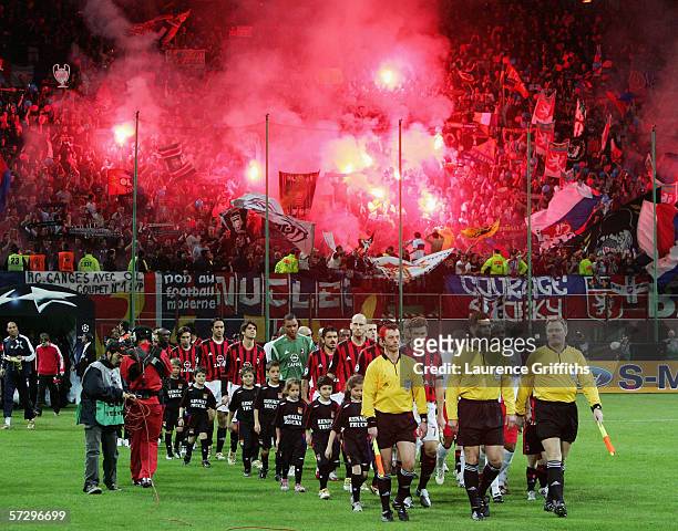 The teams walk out as the Lyon fans light flares during the UEFA Champions League Quarter Final Second Leg match between AC Milan and Lyon at the San...