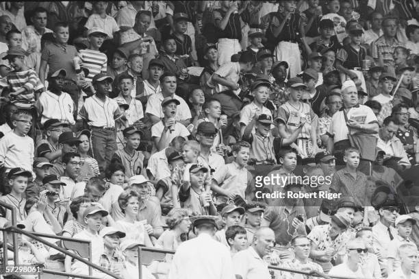 View of a number of young boys, some in various baseball uniforms, as they watch the Detroit Tigers play at Briggs Stadium, Detroit, Michigan, early...