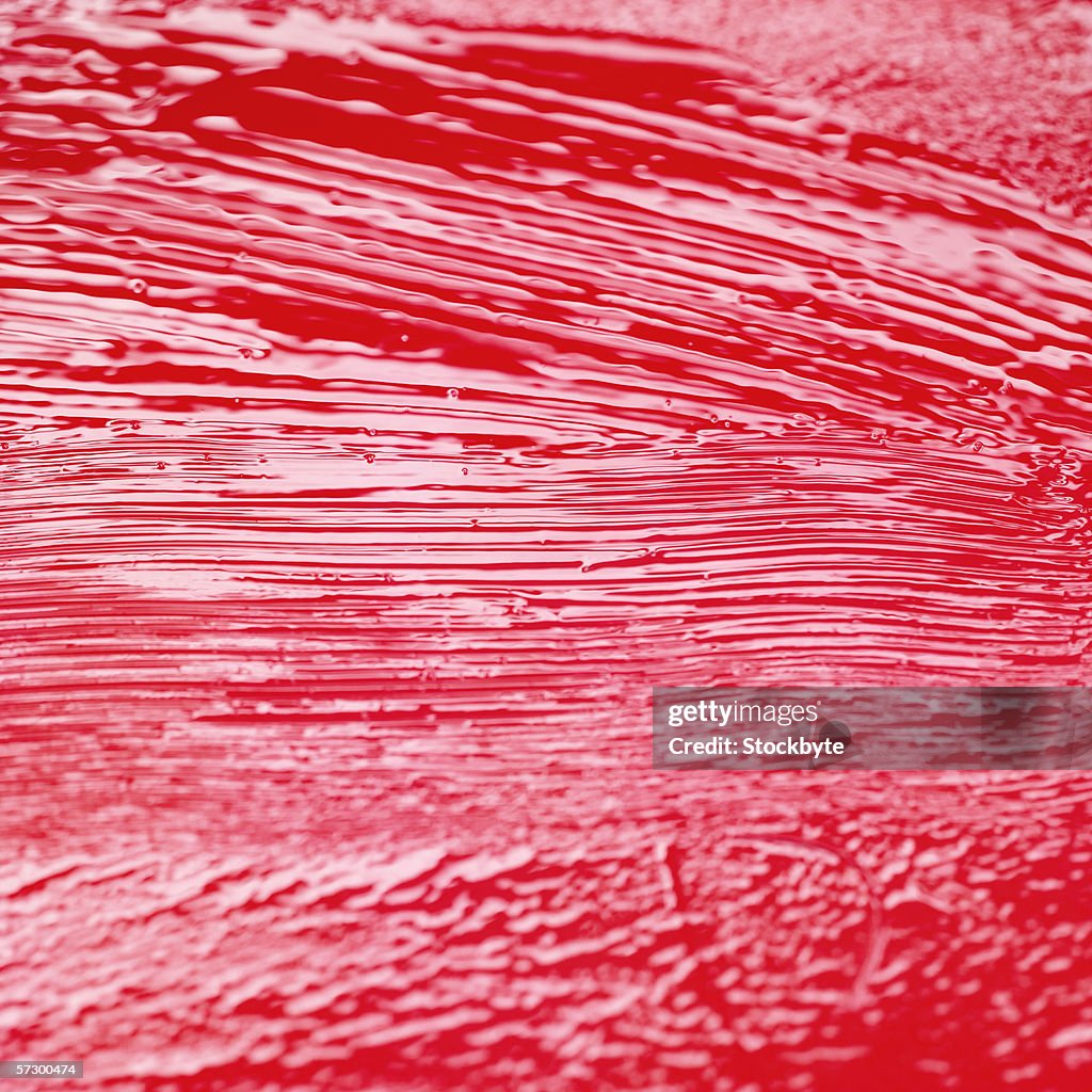 Close-up of a fresh coat of red paint on a wooden surface