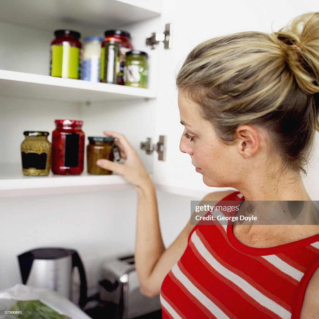 Young woman taking a jar from the kitchen cabinet