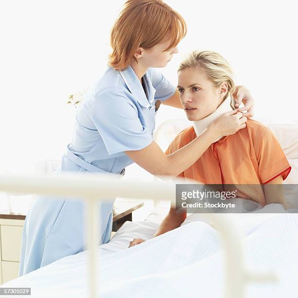 young female nurse adjusting a young woman's neck brace - collarín médico fotografías e imágenes de stock