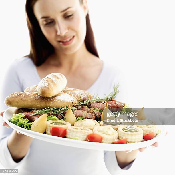 young woman holding a dish of assorted vol-au-vents served with bread and bacon rolls - vol au vent stockfoto's en -beelden