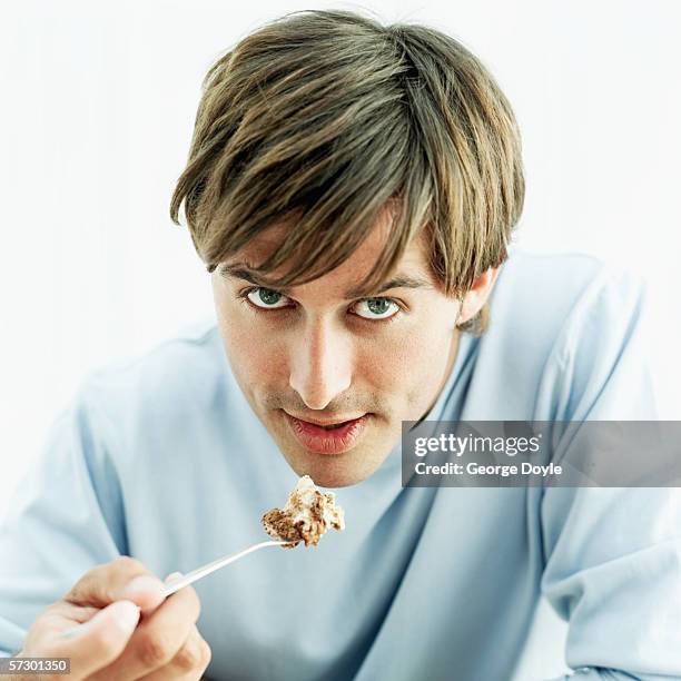 portrait of a young man eating a portion of tiramisu with a spoon - spoon in hand stock pictures, royalty-free photos & images
