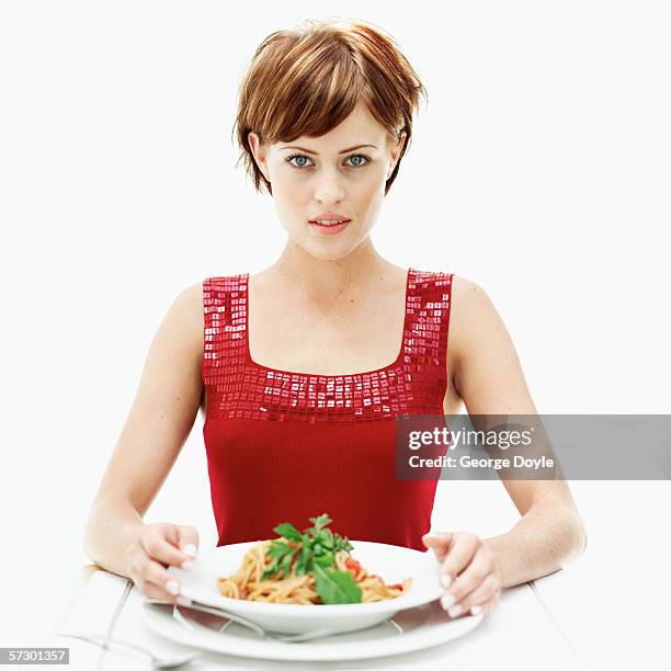 portrait of a young woman with a plate of spaghetti - pasta geniessen stock-fotos und bilder