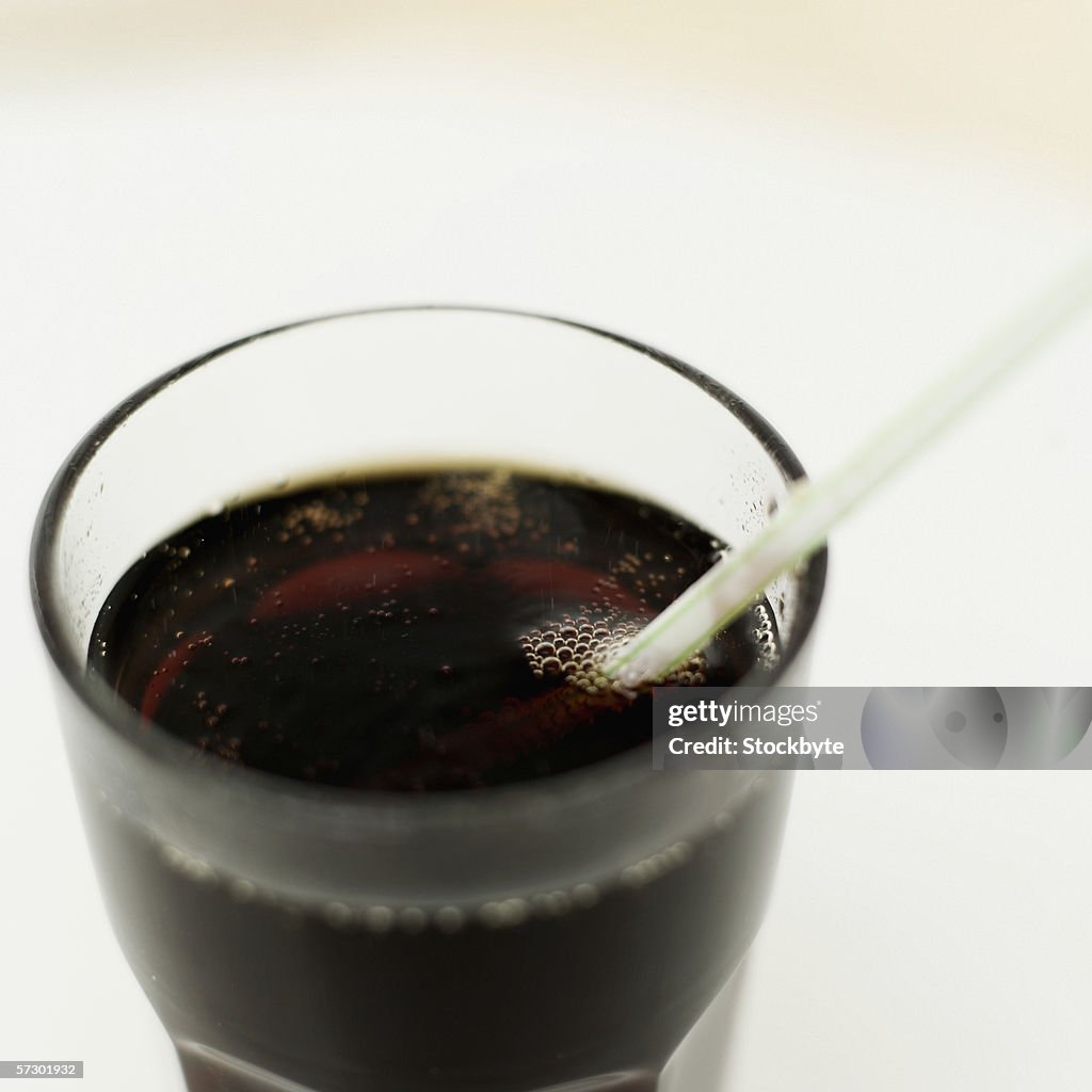 Elevated view of a glass of cola with a straw in it