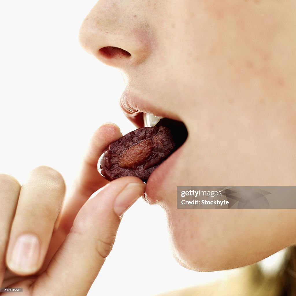 Side profile of a teenage girl (15-17) eating an olive