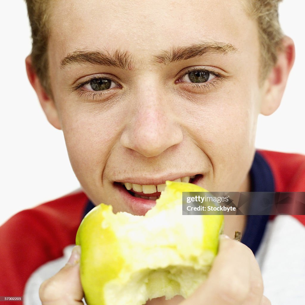 Close-up of a teenage boy (15-17) eating a green apple