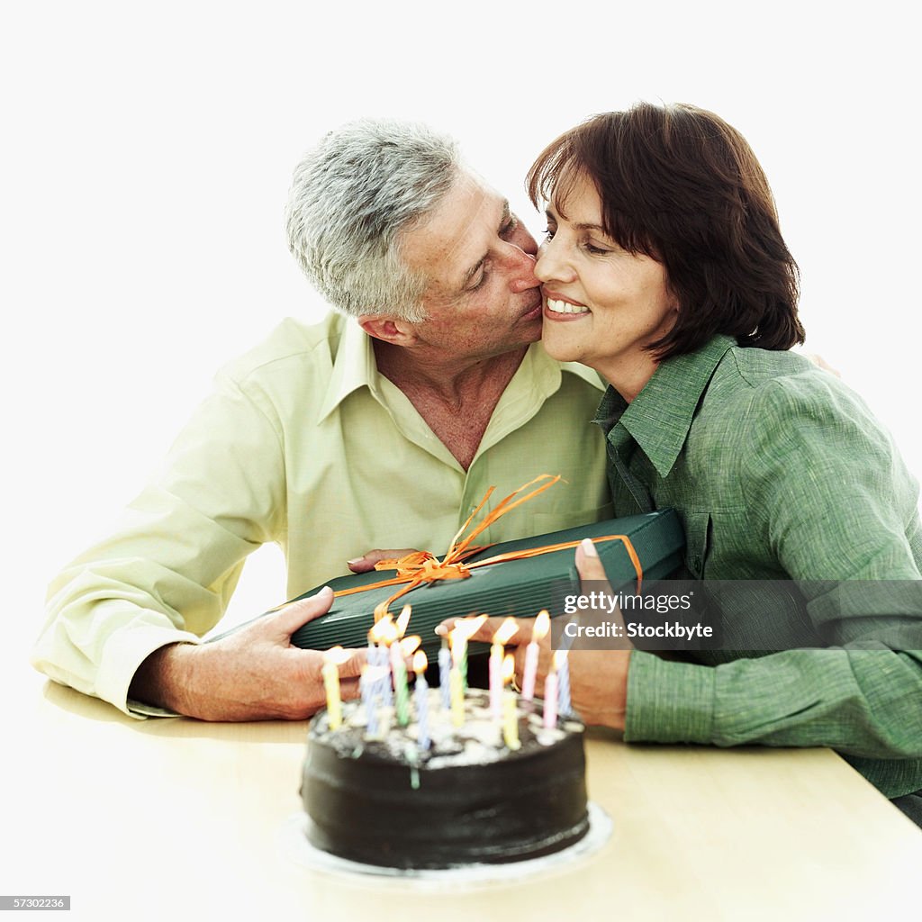 Elderly man thanking a woman for a present with a kiss