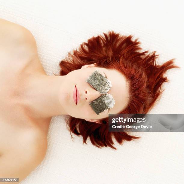 elevated view of a young woman lying down with teabags on her eyes - tea bags stock pictures, royalty-free photos & images