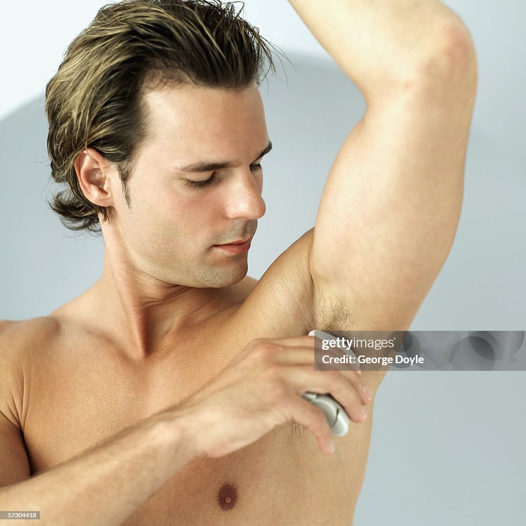 Close-up of a young man using a deodorant stick under his arm