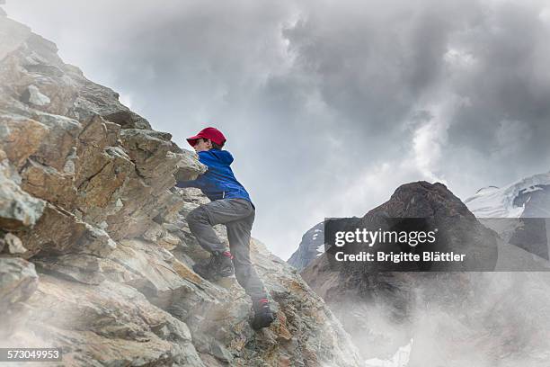 kid climbing on rock, engadin, switzerland. - boy rock climbing stock-fotos und bilder