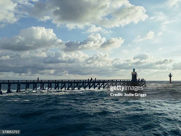 people walking along a jetty towards a lighthouse - hossegor ストックフォトと画像