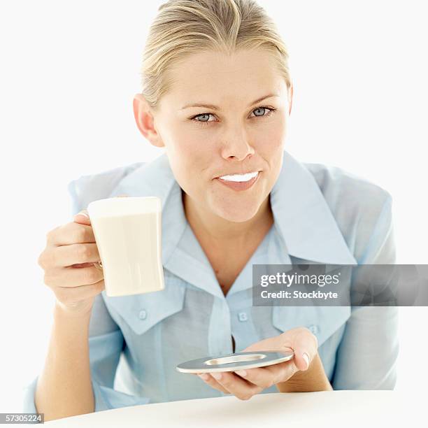 portrait of a young woman holding a cup of coffee with cream on her mouth - coffee moustache stock pictures, royalty-free photos & images