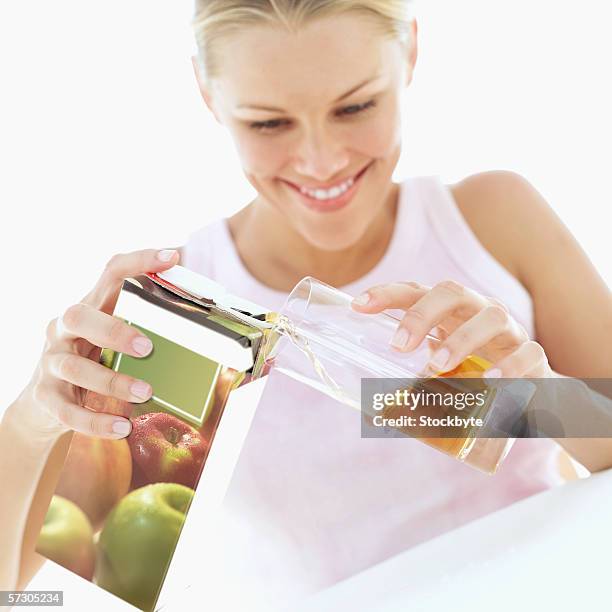 young woman smiling pouring apple juice into glass - juice box stock pictures, royalty-free photos & images