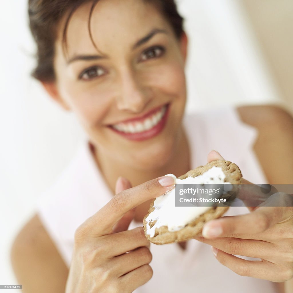 Portrait of young woman touching cheese on a cracker with her finger