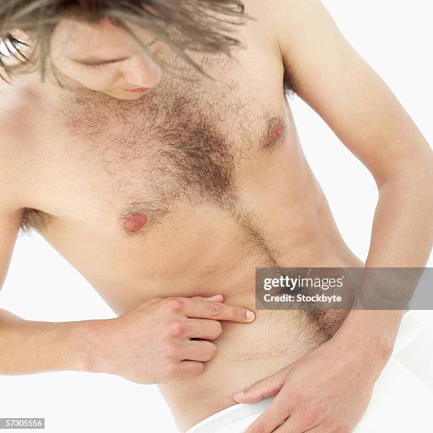 close-up of a bare chested young man checking his appendectomy scar - appendectomy stock pictures, royalty-free photos & images