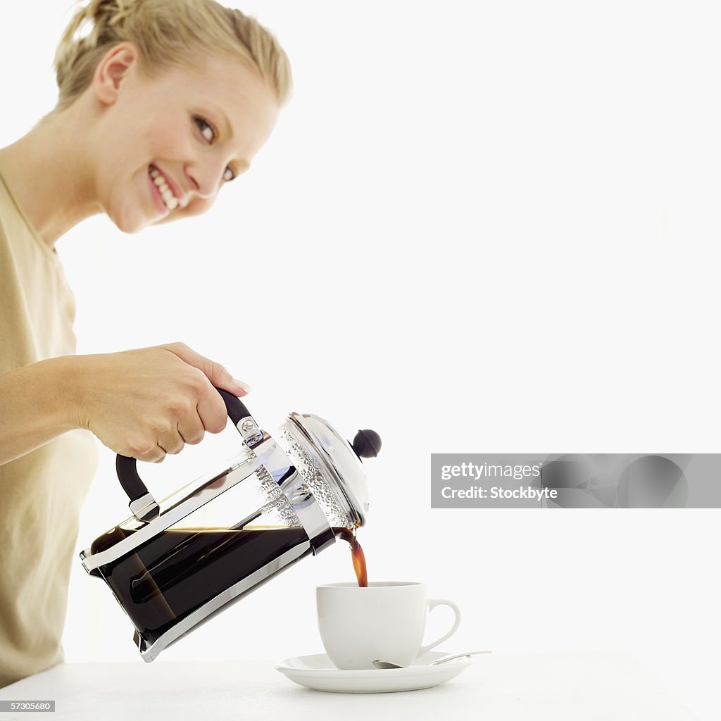 Young woman pouring coffee from a coffee press into a cup