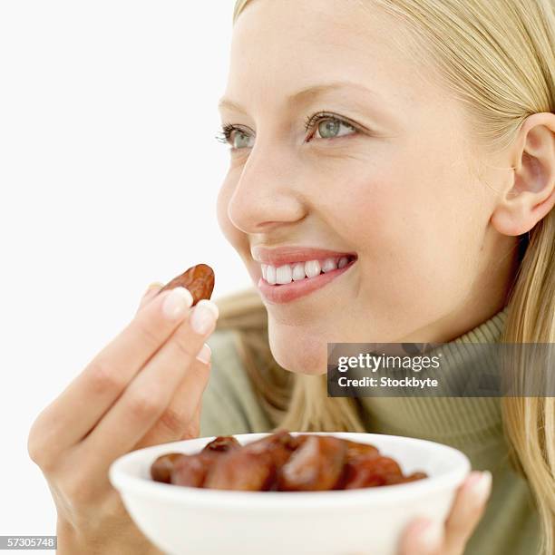 young woman eating a prune - dörrpflaume stock-fotos und bilder