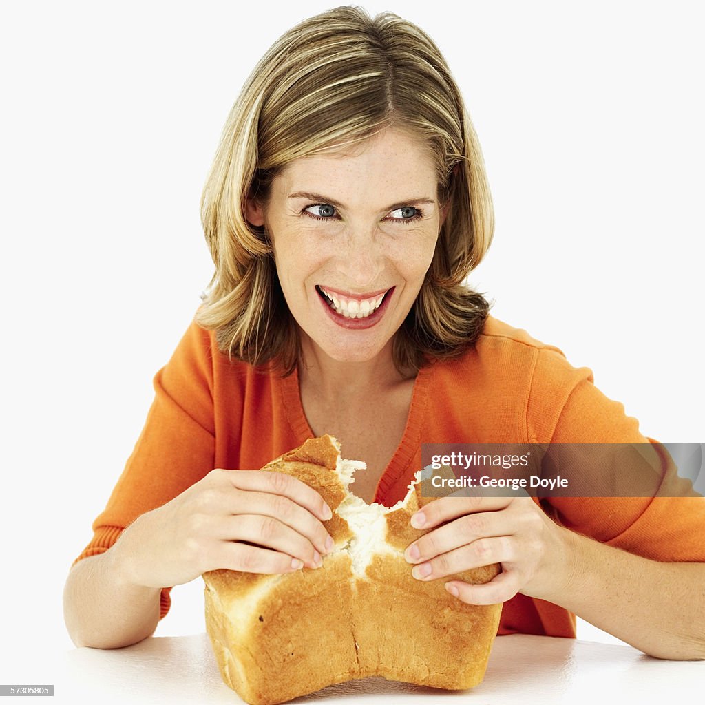 Young woman tearing open a loaf of freshly baked bread