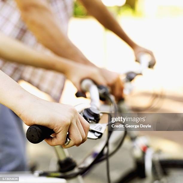 close-up of two people gripping bicycle handle bars - bike handle stock pictures, royalty-free photos & images