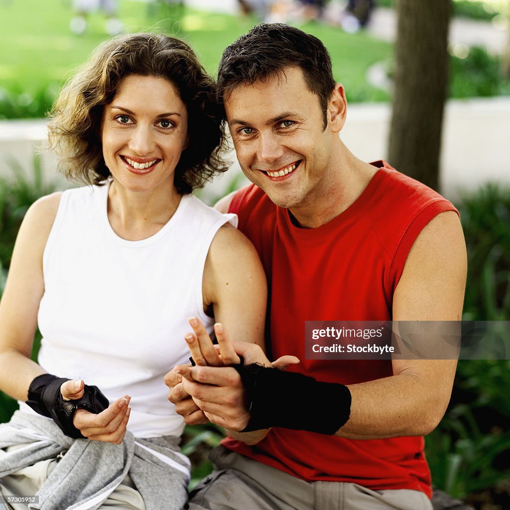 Portrait of a young couple putting on protective gloves to go cycling