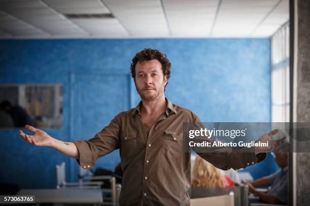 caucasian man standing with arms outstretched in living room - alberto stock-fotos und bilder