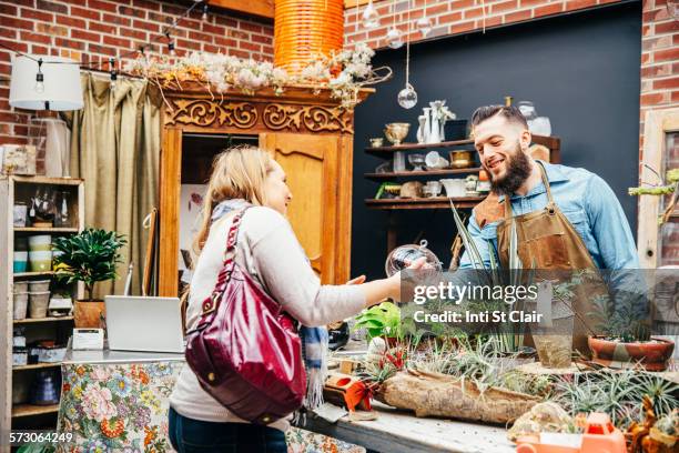 caucasian employee helping customer in plant nursery - small business saturday stock pictures, royalty-free photos & images