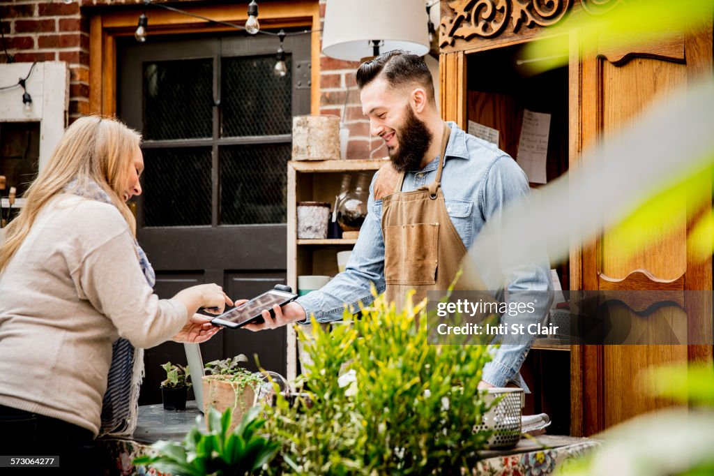 Employee helping customer with digital tablet in store