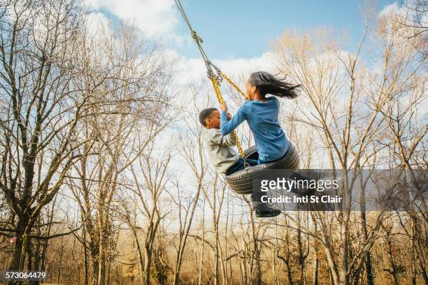black brother and sister playing on tire swing - missouri mittlerer westen stock-fotos und bilder
