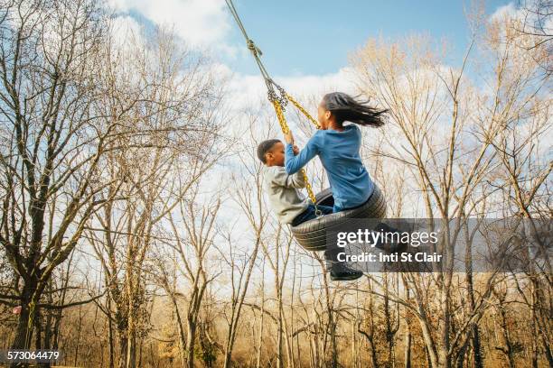 black brother and sister playing on tire swing - tyre swing stock pictures, royalty-free photos & images