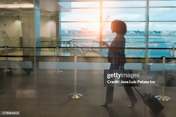 businesswoman rolling luggage in airport waiting area - roll call stock pictures, royalty-free photos & images