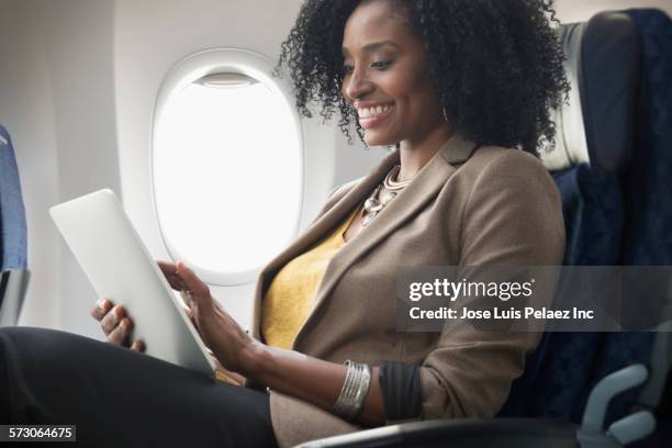 businesswoman using digital tablet on airplane - aircraft wifi stock pictures, royalty-free photos & images