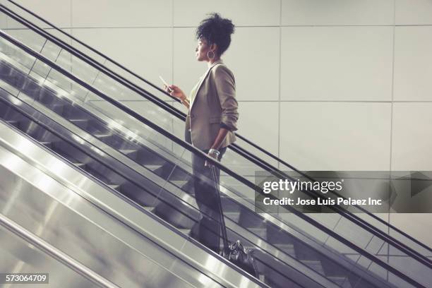 businesswoman using cell phone on escalator - escalator side view stock pictures, royalty-free photos & images