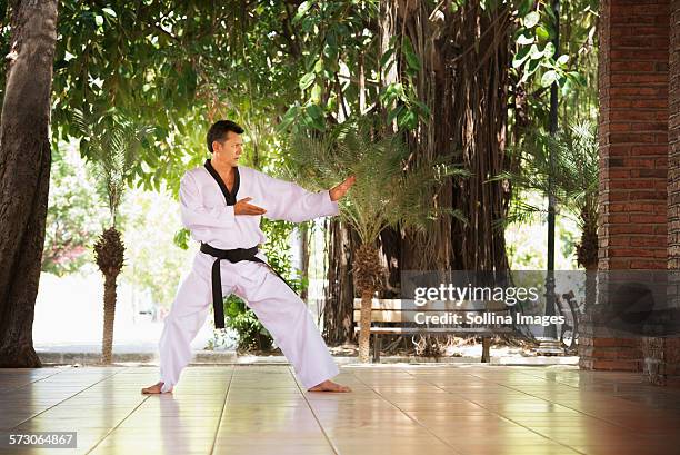 hispanic man practicing martial arts on patio - martial arts belt stock pictures, royalty-free photos & images