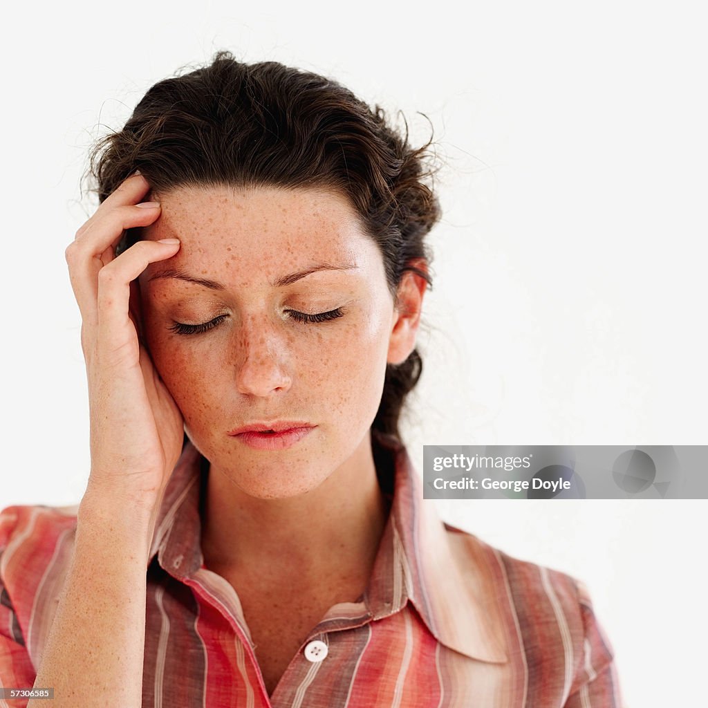 Young woman with her hand on her head and eyes closed