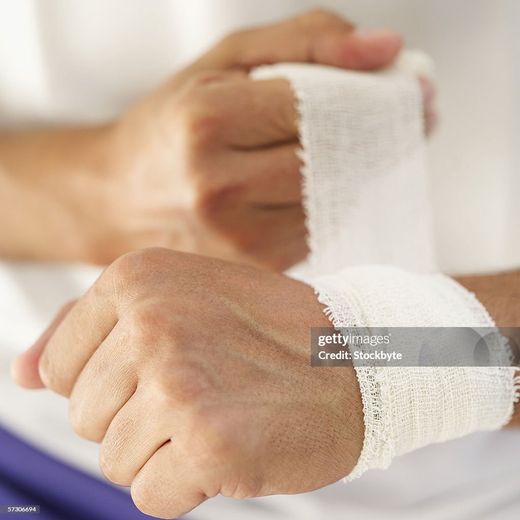 Close-up of a man's hand bandaging his wrist
