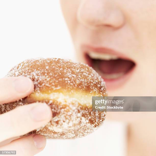 close-up of a young woman's hand holding a doughnut to her mouth - pan dulce fotografías e imágenes de stock