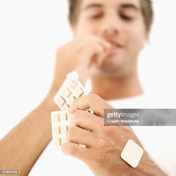 low angle view of a young man eating nicotine gum from a strip - nikotin stock-fotos und bilder