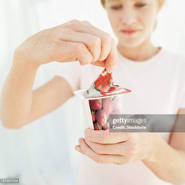 woman opening a strawberry yoghurt - yoghurt pot stock-fotos und bilder