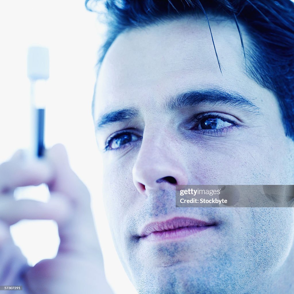 Close-up of a young man holding a test tube