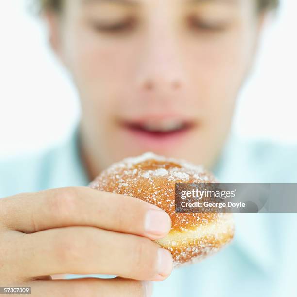 close-up of a young man's hand holding a doughnut - blue donut white background stock pictures, royalty-free photos & images