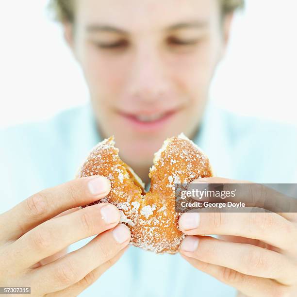 close-up of man's hands breaking a doughnut - blue donut white background imagens e fotografias de stock