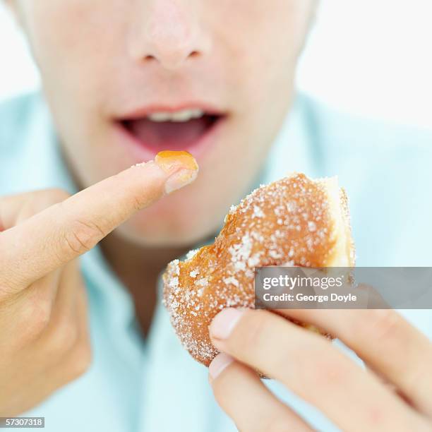 close-up of man's hands picking the filling out of a doughnut - finger bun stock pictures, royalty-free photos & images