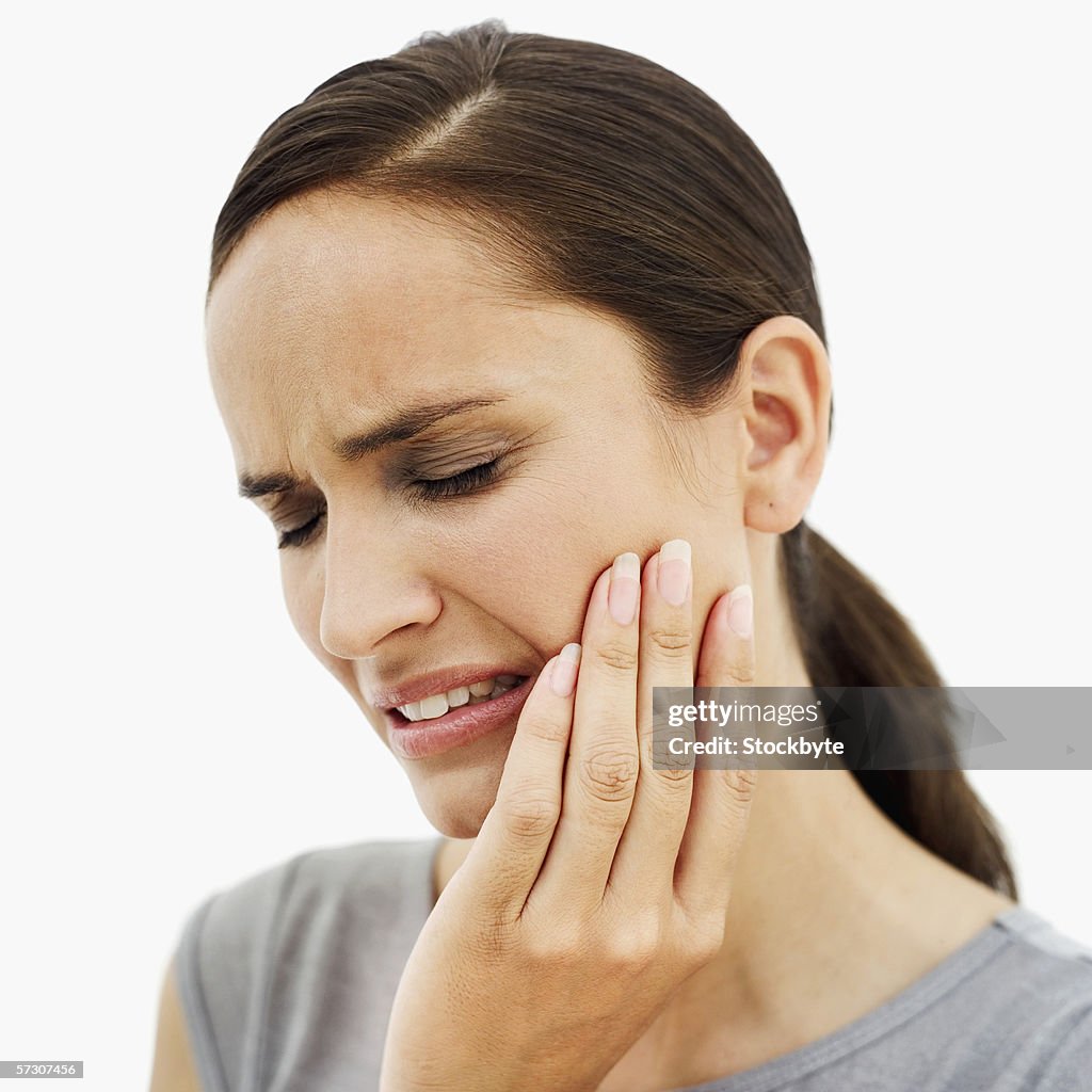 Close-up of a young woman holding the side of her face in pain